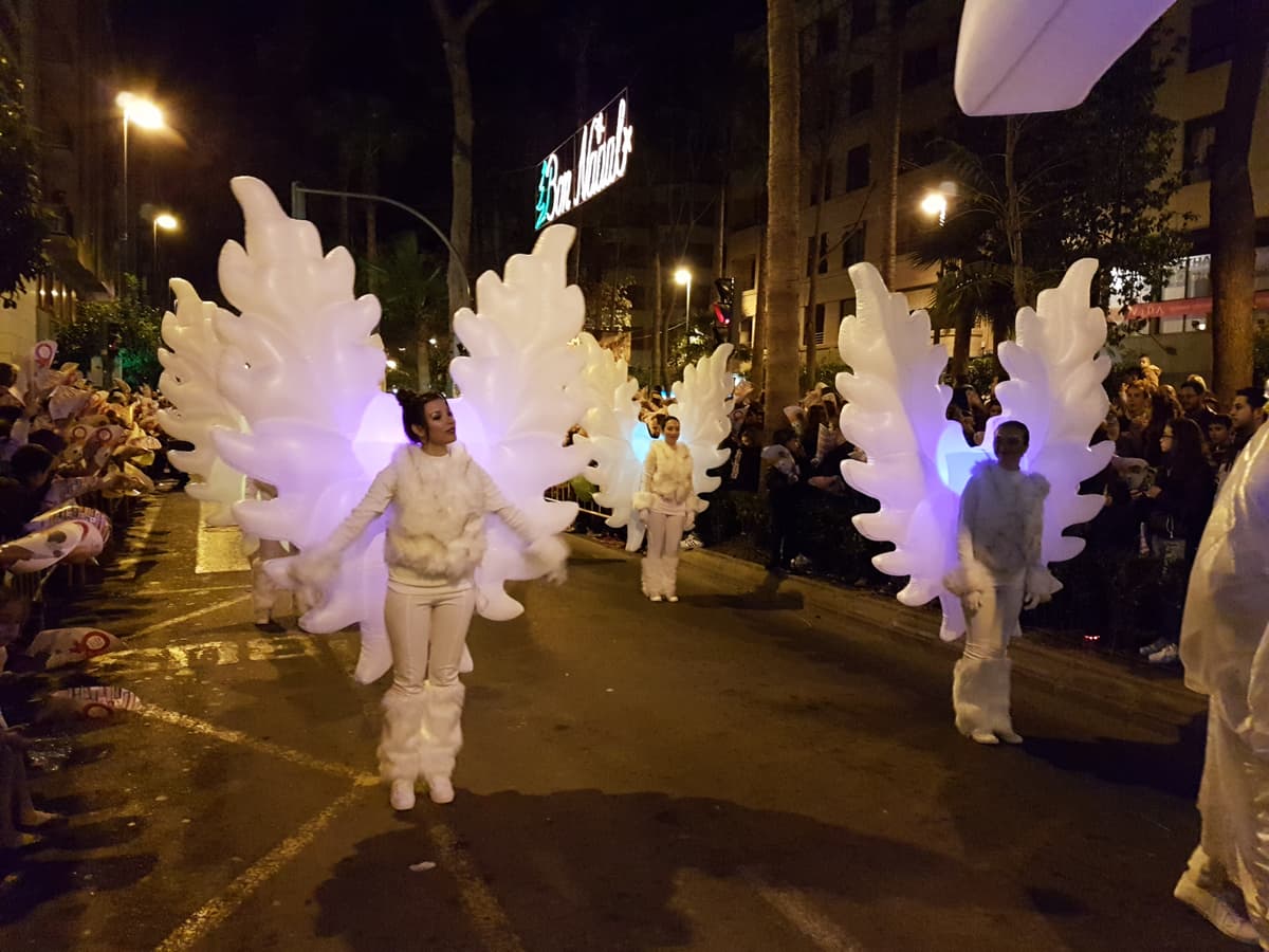 Ángeles con vestuario led iluminado avanzando en el cortejo de una cabalgata de Reyes